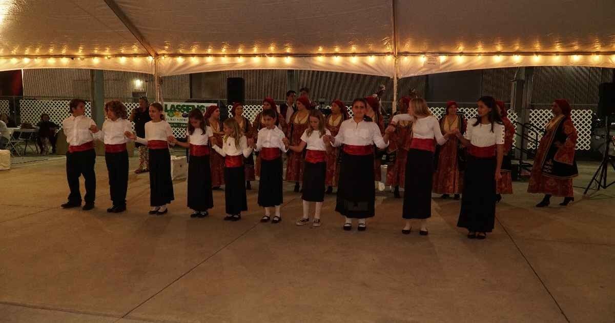 Youth folk dancers in a line under the festival tent