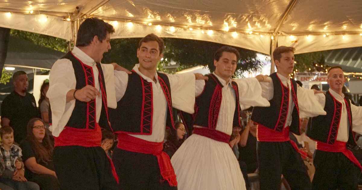 Men in traditional vest and fustanella dancing under the tent